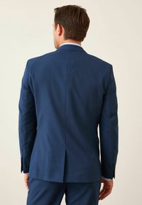 Marineblauwe blazer met een gladde textuur, een enkele split aan de achterkant en een subtiel ruitpatroon. Bevat bijpassende broek en knoopmanchetten.