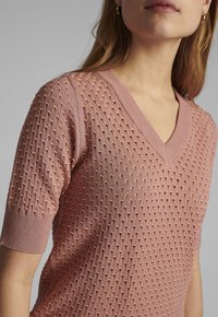 Rosa stickad kortärmad topp med V-ringning, texturerad mönster med små upphöjda prickar och ribbade ärmslut.