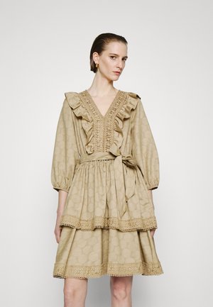 Μπεζ φόρεμα με ρυτιδωτό V-ντεκολτέ, φουσκωτά μανίκια και ζωνάκι στη μέση. Διαθέτει υλικό με υφή και δαντέλα στο στρίφωμα.