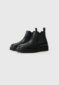 Botas Chelsea de cuero negro con paneles elásticos en los laterales, punta redonda y suela de goma texturizada. Acabado suave y lengüetas de tirón para ponerlas fácilmente.