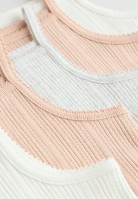 Tre canotte a coste in morbidi colori pastello: rosa chiaro, grigio e bianco. Ognuna presenta bordi a scalloped e un tessuto strutturato.