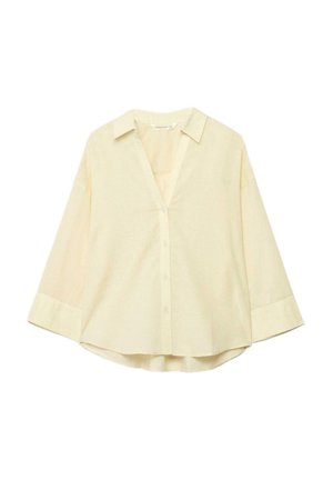 Krémovo sfarbená blúzka s dlhým rukávom, s golierom, zapínaním na gombíky vpredu a mierne zaobleným lemom, zobrazená na bielom pozadí.