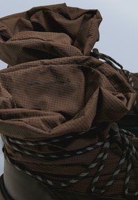 Cizme de izolație termică maro, cu partea superioară din țesătură texturată, șireturi cu model alb-negru și design cu manșetă pentru căldură suplimentară.