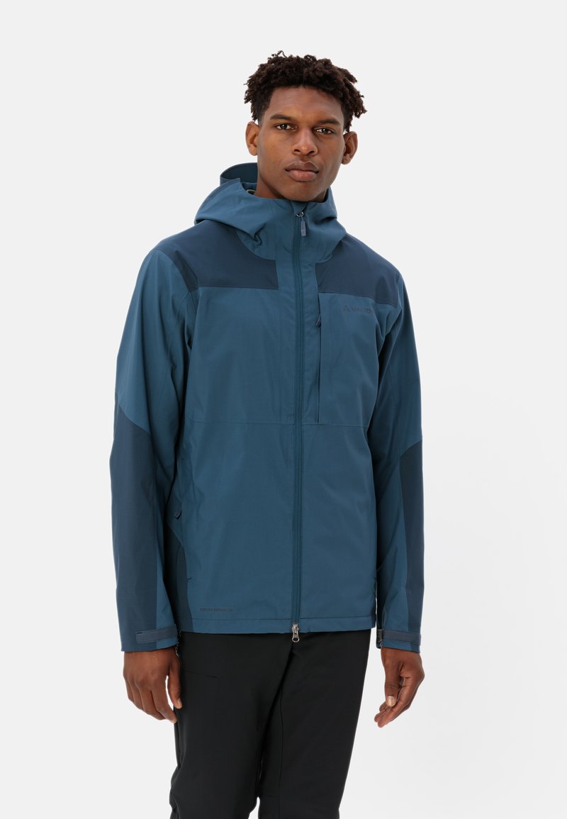 Giacca da trekking blu impermeabile con cappuccio, zip frontale e tasca sul petto. Presenta accenti in blu scuro a contrasto e polsini regolabili.