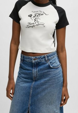Kvinde iført en sort-hvid crop top med en pizza slice-tegneserie, der holder et hjerte med teksten "Hug" og teksten "Pizza My Heart True Dough-mance."