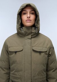 Parka khaki con cappuccio, dotata di due tasche sul petto, cappuccio regolabile e cordini a contrasto. Realizzata in tessuto testurizzato e durevole.