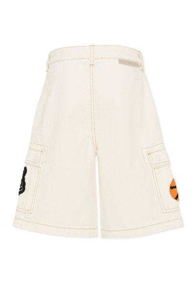 Shorts amples couleur ivoire avec poches plaquées à l'avant, patchs brodés orange et noirs sur les côtés, et surpiqûres orange visibles.