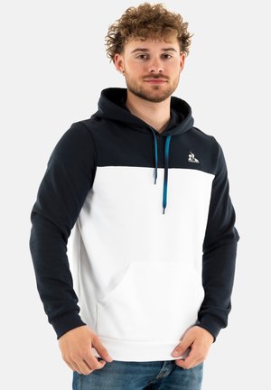 Sudadera con capucha que tiene una sección superior en color azul marino y una sección inferior en color blanco. Cuenta con un cordón azul, un bolsillo frontal y un logo en el pecho.