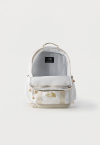 Λευκό και μπεζ σακίδιο πλάτης North Face με ανοιχτό το κύριο διαμέρισμα και μερικώς ανοιγμένο το μπροστινό φερμουάρ, σε λευκό φόντο.