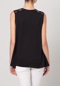 Schwarzes ärmelloses Oberteil mit Spitzenapplikationen auf den Schultern, mit lockerem Schnitt und leicht geschwungenem Saum, aus leichtem Stoff gefertigt.