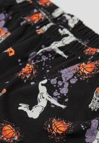 Černé bavlněné šortky s opakujícím se vzorem inspirovaným basketbalem, který tvoří oranžové basketbalové míče a bílé siluety hráčů na purpurových skvrnách.