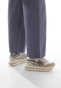 Sportliche Sneakers in Beige, Weiß und schwarzem Leopardenmuster. Mit pinken Schnürsenkeln, dicker Sohle und strukturiertem Obermaterial aus verschiedenen Schichten.