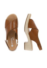 Brown leather sandals with crossed straps, open heel, and textured light wood block heel. Lightly cushioned insole.
