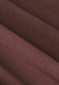 Tissu bourgogne avec une texture douce, présentant une finition lisse et un motif de tissage subtil, plié pour créer des ondes douces.