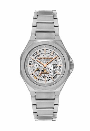Silverfarvet Armani Exchange automatisk armbåndsur med skelet urskive, gyldne accenter og kædet metalrem.