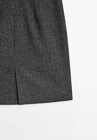 Grå herringbonekjol med rak silhuett och sidslits, tillverkad av textil med struktur, med subtila kontrasterande trådar.