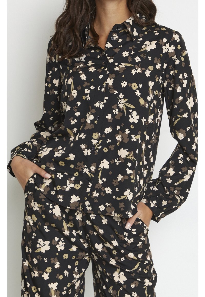 Czarna koszula zapinana na guziki w kwiaty z kremowymi i oliwkowymi kwiatami, długimi rękawami oraz luźnym krojem i kołnierzykiem z ostrym zakończeniem.