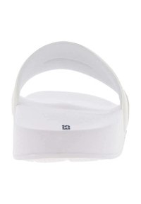 Sandalia plana blanca con suela plana y diseño de tira redondeada, con una textura suave y un sutil estampado de marca en el lateral.