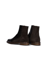 Bruine suède enkelboots met een textuur paneel van zwart leer, ronde neus en een ritssluiting aan de achterkant. Houten hak en gladde neuskap details.