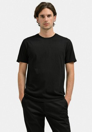 Sort bomulds t-shirt med rund halsudskæring, korte ærmer og almindelig pasform. Bære sammen med matchende sorte bukser. Ingen synlige mønstre eller logoer.