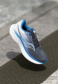 Baskets de course avec une tige en mesh grise et blanche, accents bleus, panneaux texturés et une semelle blanche rembourrée. Présente un design à lacets.