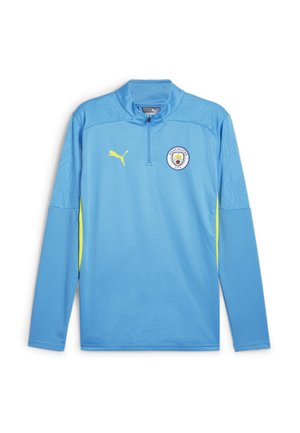 Haut de sport à manches longues bleu clair avec demi-fermeture éclair, accents jaunes, tissu texturé et logo de Manchester City sur la poitrine.