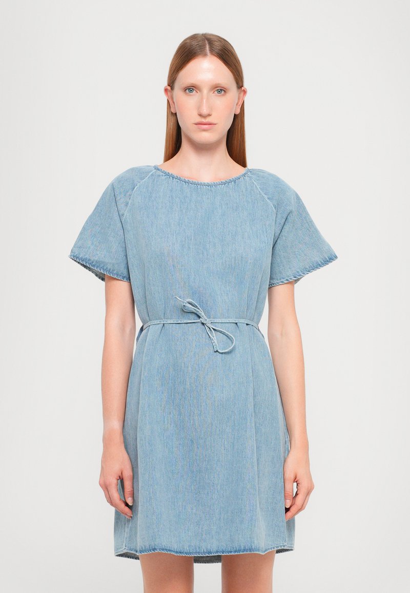 Φόρεμα από ανοιχτό μπλε τζιν με κοντά μανίκια, στ�ρογγυλή λαιμόκοψη και ζώνη δέσιμο στη μέση. Περιλαμβάνει ορατές ραφές και άνετη εφαρμογή.
