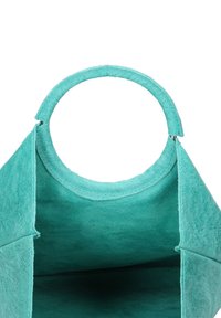 Turkoois vilten handtas met een ronde handgreep en een open bovenkant, met een zachte textuur en zonder zichtbare bevestigingsmaterialen of sluitdetails.