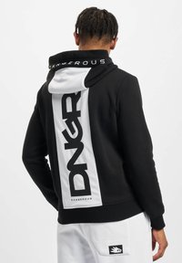 Felpa nera con accenti bianchi, caratterizzata da un grande logo "DNGR" sul retro. Il materiale sembra morbido e testurizzato con un design con cappuccio.