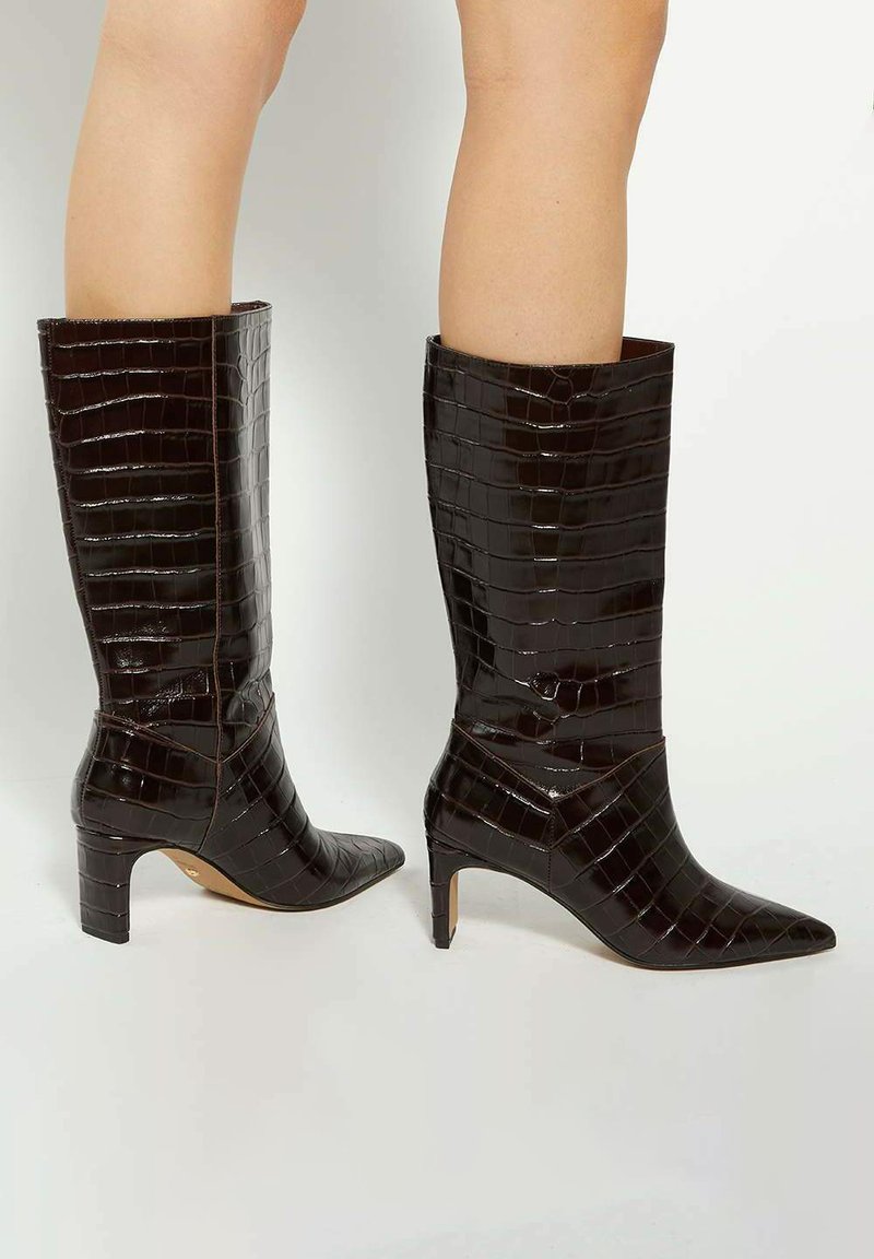 Knee-high black patent leather boots with an alligator texture, pointed toe, and a slim, short heel. Features diagonal seam accents.