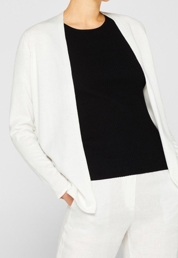 White open-front cardigan over a black ribbed top, paired with light-colored pants. Soft fabric, relaxed fit, and no fasteners visible.