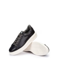 Zapatillas de cuero negro con suelas de goma blanca, con punta redonda, diseño de cordones y plantillas texturizadas, exhibición en ángulo con ligera sombra.