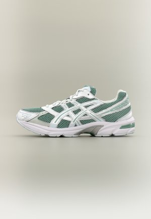 Chaussure de sport verte et blanche avec une tige en mesh, un col rembourré et une semelle intermédiaire amortissante, dotée d'une semelle extérieure en caoutchouc texturée pour une meilleure traction.
