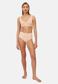 Bralette rosa chiaro con spalline larghe e scollatura a V profonda, abbinata a mutandine a vita alta dello stesso colore; materiale morbido e design senza cuciture.