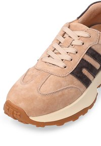 Beżowe zamszowe sneakersy z brązowymi akcentami, z zaokrąglonym noskiem, wyściełanym językiem i teksturowaną gumową podeszwą. Sznurowadła w dopasowanym kolorze.