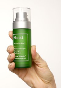 Grön glasflaska med ett silverpumpsystem, märkt "Murad Resurgence Retinal ReSculpt Overnight Treatment." Slät yta, tydlig varumärkesprofil.