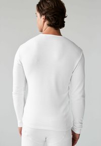 Cămașă albă cu mânecă lungă, confecționată din material ribatat, cu un design ajustat, guler rotund, umeri fără cusături, asortată cu o piesă de îmbrăcăminte albă pentru partea de jos.