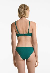 Teal bikini-set med en texturerad, ribbad design. Toppen har justerbara remmar och en krokstängning, med en klassisk bikiniunderdel.
