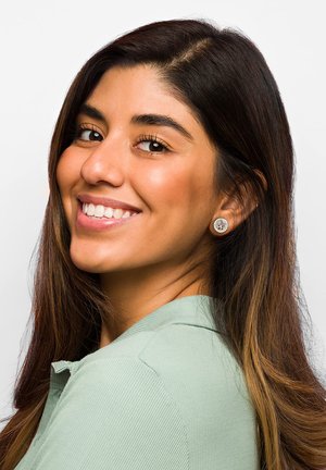 Silverfärgade studs med intrikata mönster, rundad form, bärs av en person med långt, mörkt hår i en ljusgrön skjorta med krage.
