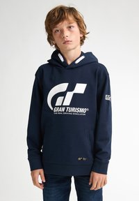 Mörkblå hoodie i bomullsblandning, med en vit logotyp på framsidan, främre ficka och dragsnören för justering av huva.