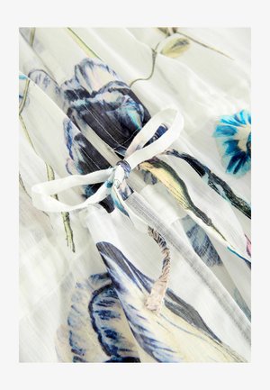 Der florale Chiffonstoff hat einen weißen Hintergrund mit blau-lila Blumenmustern. Ein gebundener Taillendetail zeigt eine leichte und luftige Textur.