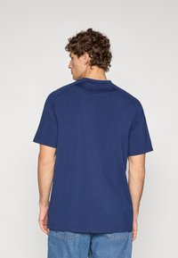 Μπλε σκούρο μπλουζάκι με κοντά μανίκια, άνετη εφαρμογή, στρογγυλή λαιμόκοψη και λεία υφή. Διαθέτει ραγκλάν μανίκια και ίσια τελείωμα.