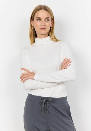 Bílý dlouhý rukáv rolák z lehkého materiálu, spárovaný se šedými kalhotami na stažení s uvolněným střihem a hladkou texturou.