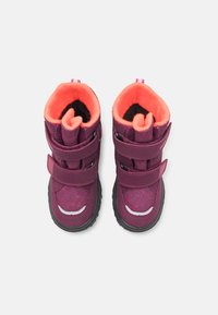 Lila Winterstiefel mit zwei Klettverschlüssen, orangefarbigem Fleecefutter, strukturiertem Äußeren und rutschfesten Sohlen aus schwarzem Gummi.