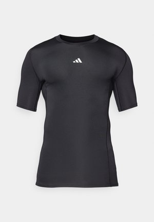 Camisa desportiva preta de manga curta feita de um tecido liso e elástico. Apresenta um logo branco no peito e costuras planas para maior conforto.