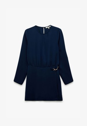 Granatowa sukienka z długim rękawem, z zaciśniętym w pasie krojem, ozdobiona złotym łańcuszkiem i okrągłym dekoltem. Gładki, lekki materiał.
