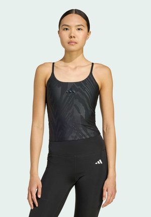 Top sportivo nero con spalline sottili caratterizzato da un sottile motivo zebras, abbinato a leggings neri a vita alta con un accento di logo.