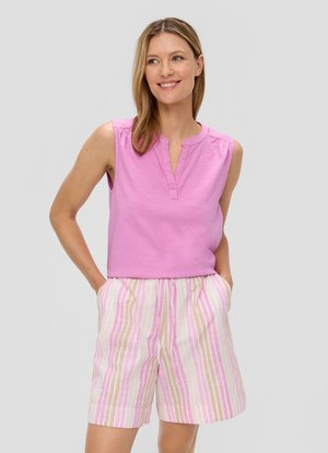 Roze mouwloos topje met een V-hals en ruches, gecombineerd met lichtgestreepte shorts met verticale lijnen in roze, beige en wit.