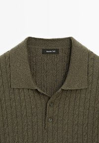 Polo shirt verde oliva in maglia con motivo a treccia, colletto corto e due bottoni davanti. Etichetta visibile con il marchio "Massimo Dutti".