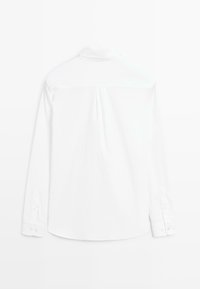 Camicia bianca a maniche lunghe con colletto classico, tessuto morbido, spalla dietro e polsini con bottoni. Design semplice e sartoriale.